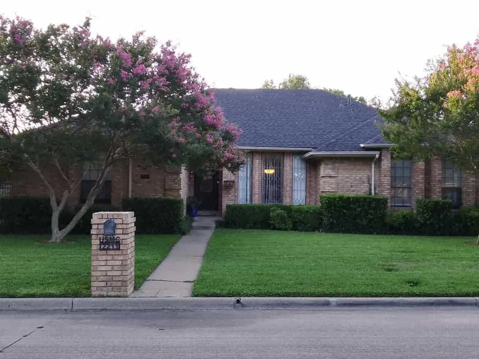 Tan brick home with a finished dark shingle roof