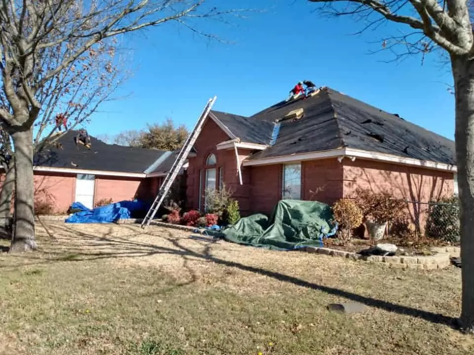 Roofers installing underlayment on a brick home