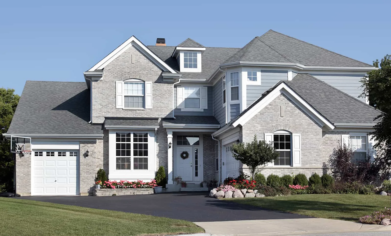 Residential home with a completed gray shingle roof under a clear sky